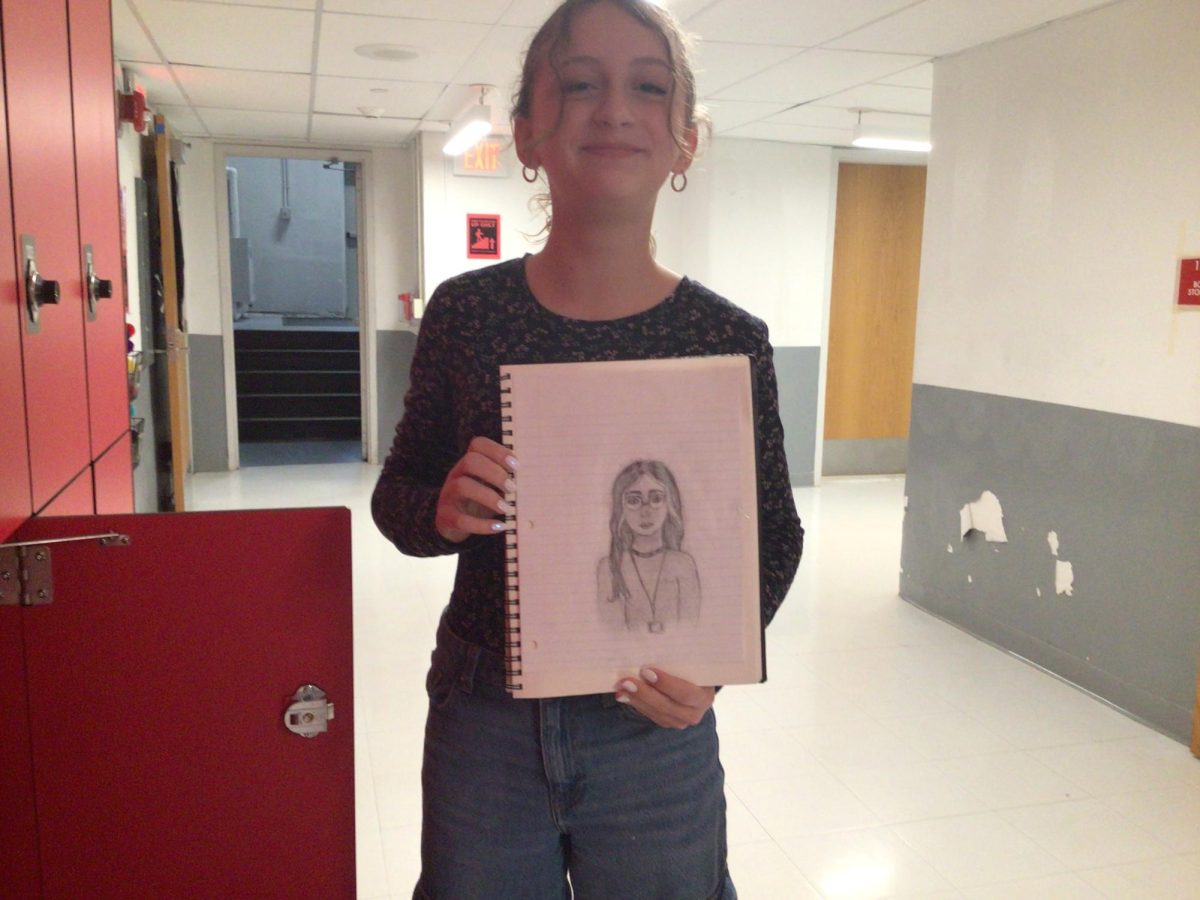 Caption: Gabby smiling for the photo with her art work
