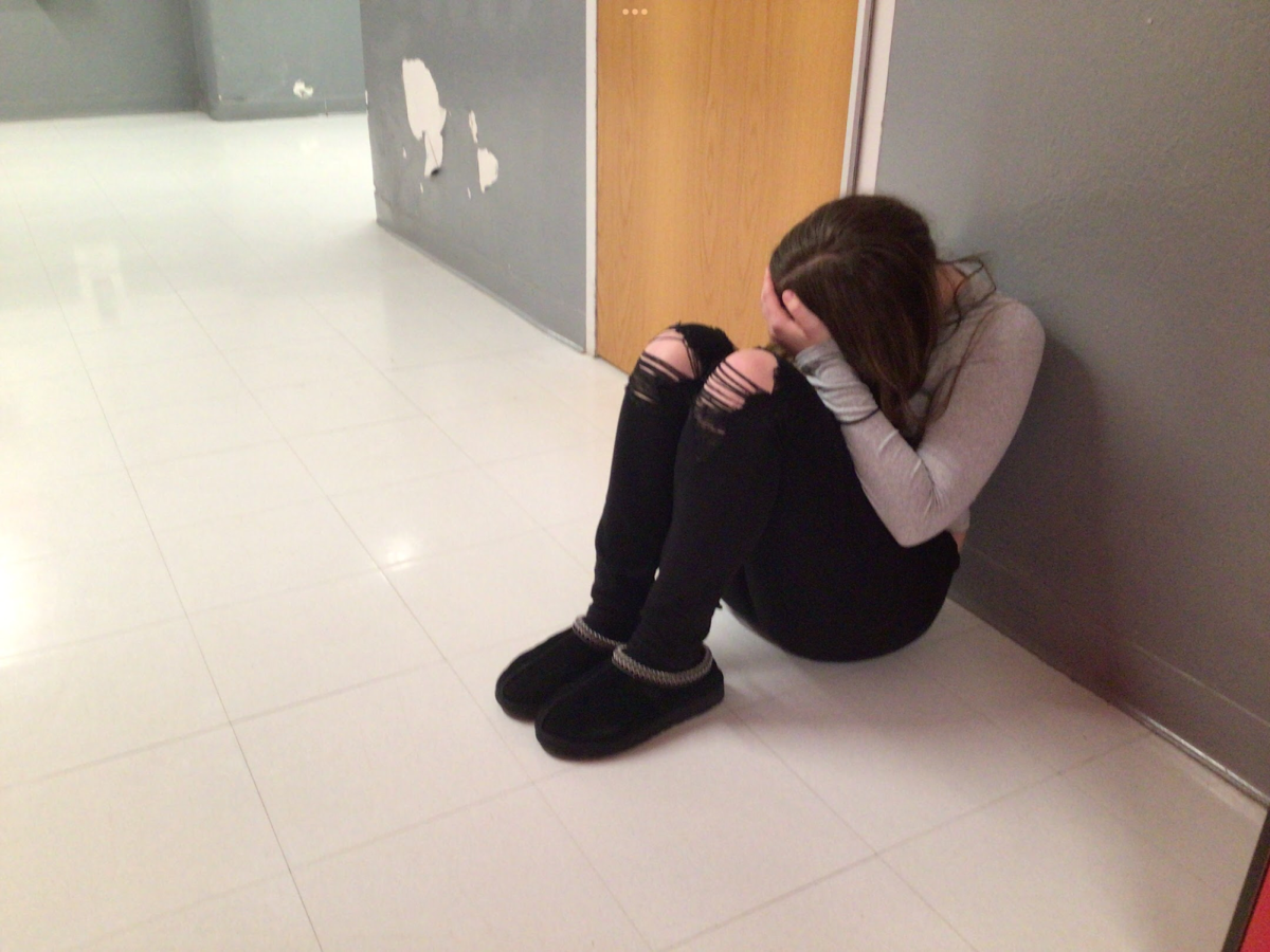A girl kneels down in the hallway experiencing a rough day. This would happen less if people opened their heart to kindness. 