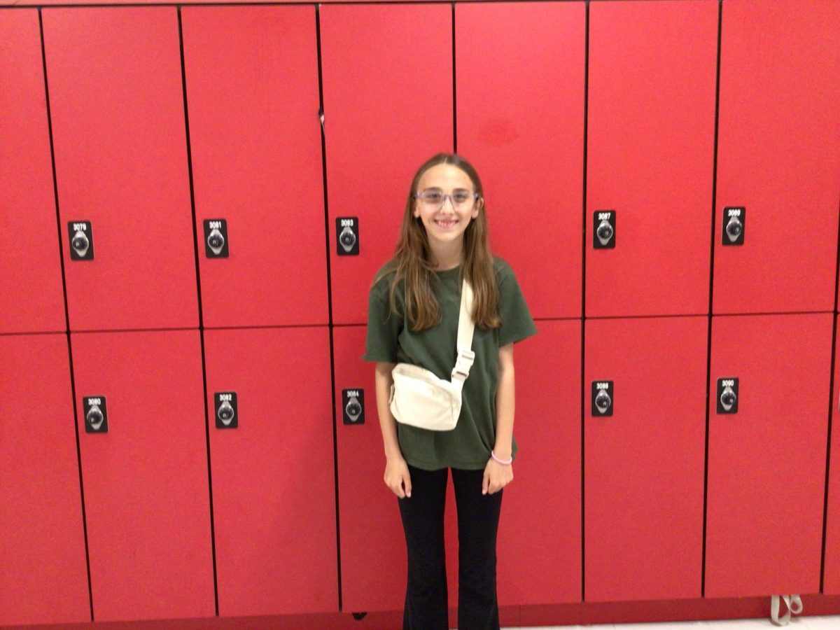 Stella poses for a picture next to the lockers by room 307