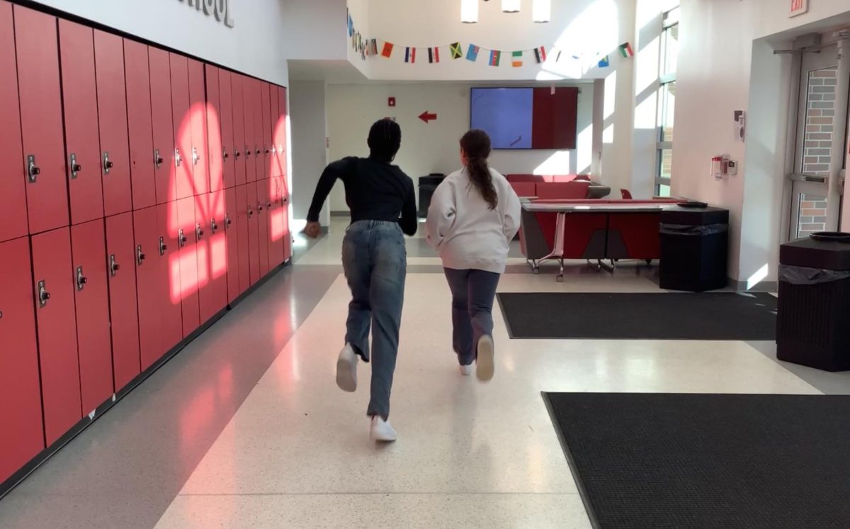 Hannah Amusa and Mia Pisapia run for a photo in the lobby of WMS.