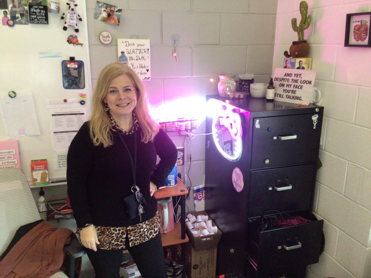 Mrs. Duffy poses for a picture at her desk