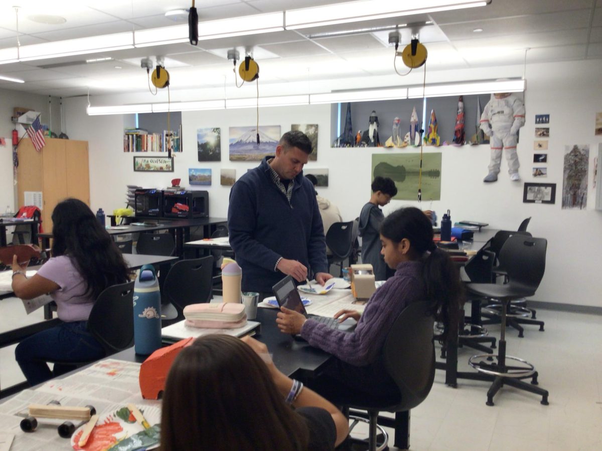 Mr. Olveson helps his student with painting