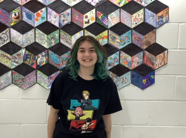 Stephanie Perugini poses for a photo in front of art wall. 