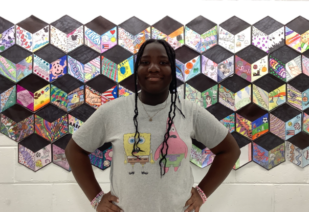 Maitee Benjamin poses for a photo in front of art wall.