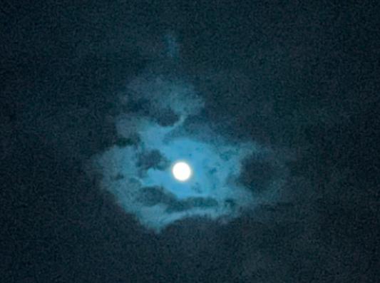 Picture of the moon surrounded by clouds with a blue tint

