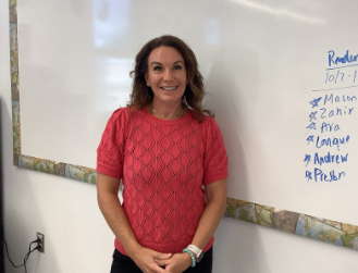 Mrs. Sweeney poses in front of whiteboard.