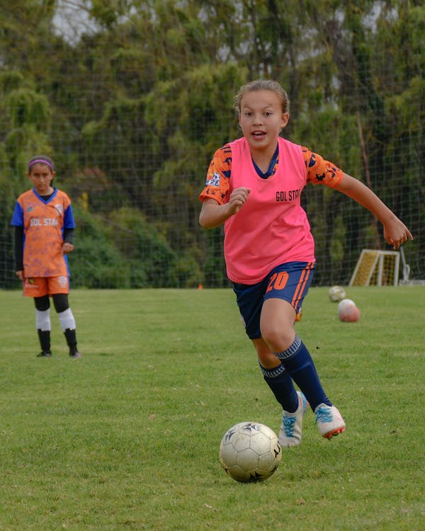 Photo from https://www.pexels.com/photo/girl-running-with-ball-on-match-16248866/ under the Creative Commons License