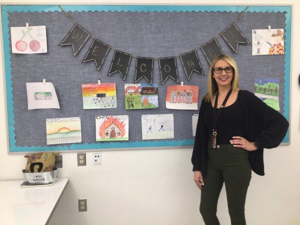 Mrs.Douglas proudly stands behind the wall of art, inspired by The Outsiders.