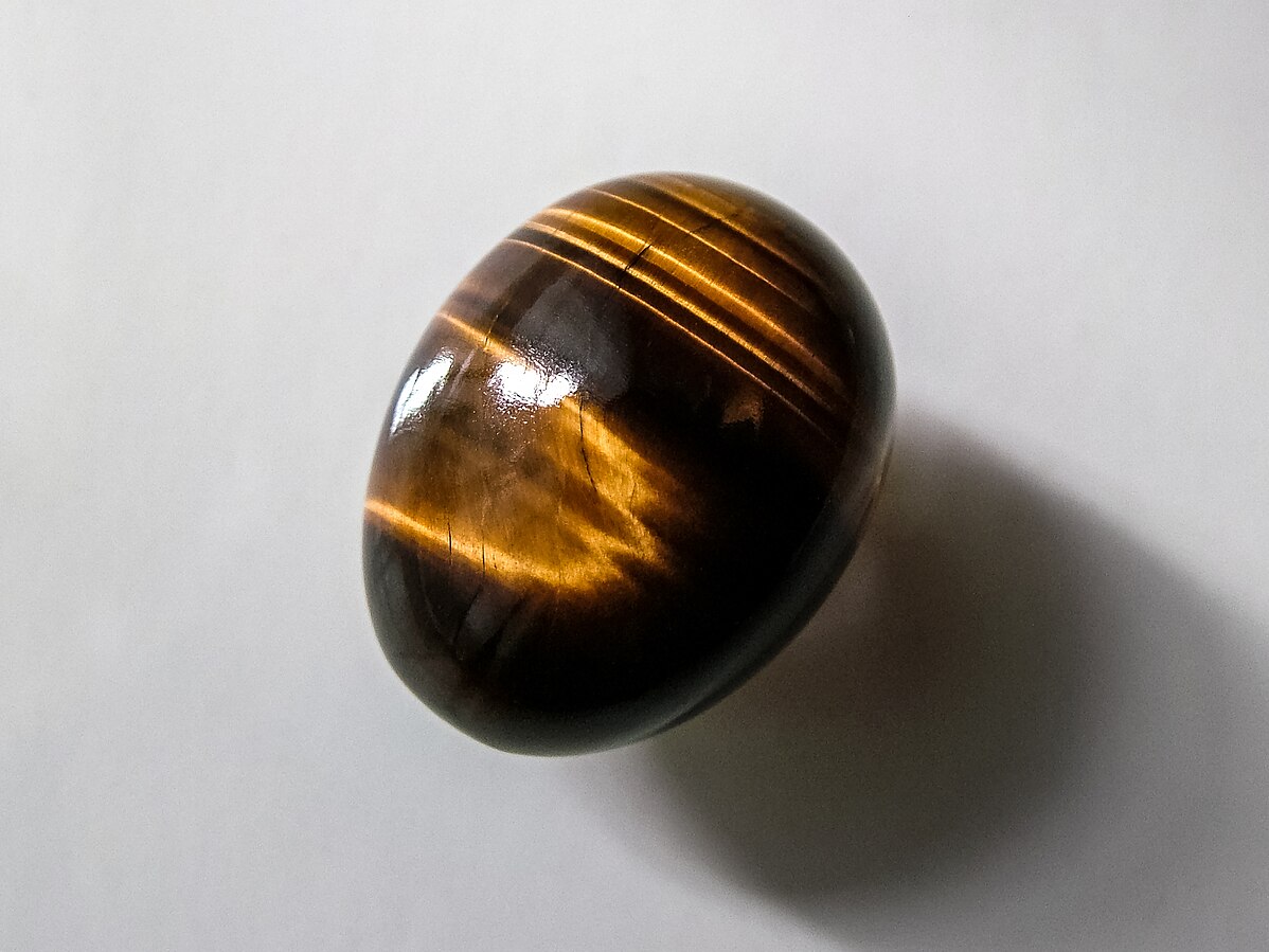 Egg-shaped golden brown tiger's eye quartz, about 2.5 cm long. Studio photography in Vibble, Visby, Gotland, Sweden.