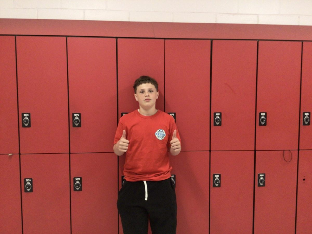 Elliot- Cardet- Merrill poses for photo in front of room 308
