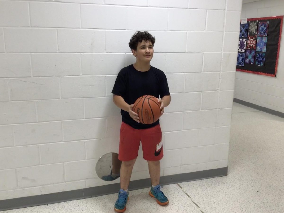 Jacob Flores poses with a basketball outside of the gym.