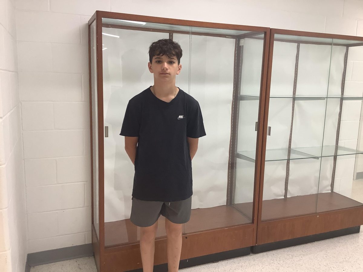 Dylan Dwyer stands in front of the shelves by the gymnasium