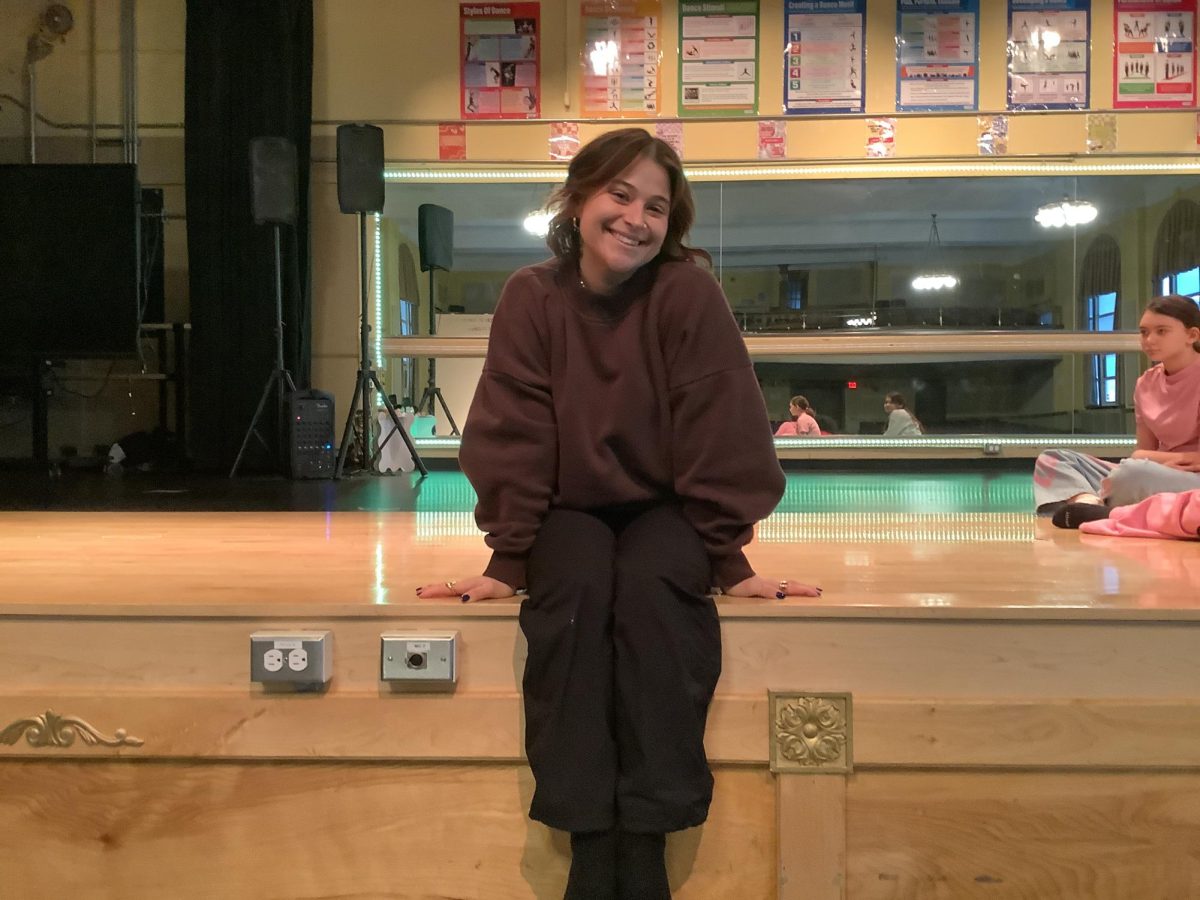 Ms. Carelli sitting on the stage in the auditorium.
