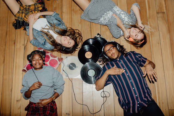 4 teens laying on the ground with a bunch of CDs