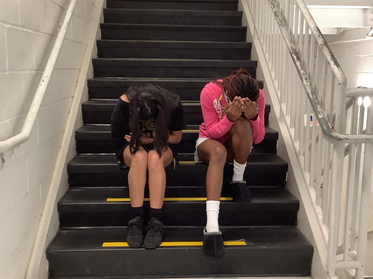 Lyric and Hannah sit and cover themselves on the stairs.